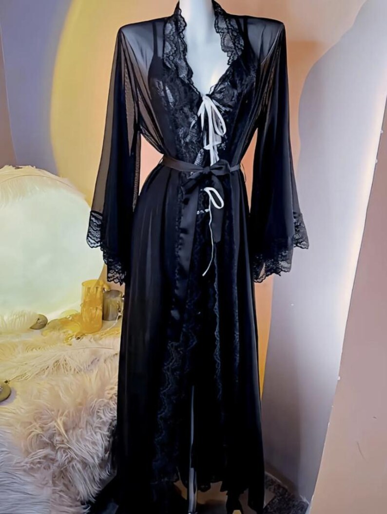 May include: A black sheer robe with lace trim and a satin sash. The robe has long sleeves and a V-neckline.