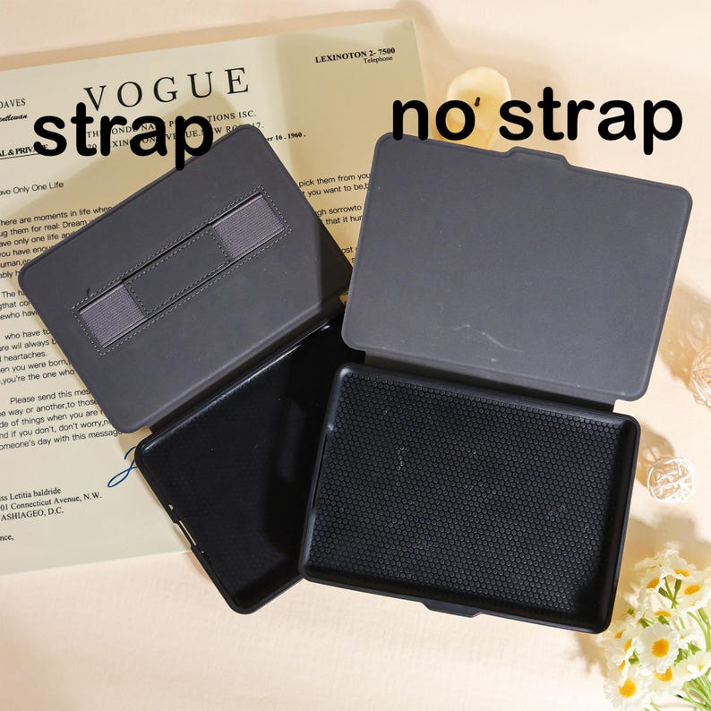 May include: Two open black tablet cases, one with a strap and one without. The cases are on a beige background with text from a magazine. The text "strap" and "no strap" are written on the image.