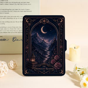 May include: A black e-reader cover featuring a detailed illustration of a crescent moon over a mountain landscape, a winding path, a lantern on books, and roses. The text THE MIDNIGHT READER is printed in a decorative frame at the bottom of the cover.
