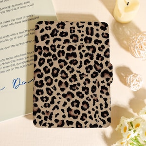 Puede incluir: Una funda con estampado de leopardo marrón y beige. La funda tiene un cierre magnético y está diseñada para guardar una tableta o un lector de libros electrónicos. La funda está hecha de un material duradero y presenta un diseño clásico de estampado animal.
