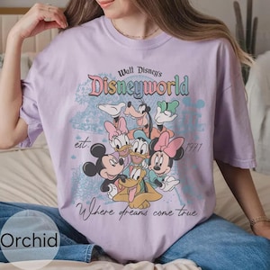 Op de afbeelding: Lichtpaars T-shirt met een Disney World-afbeelding met Mickey en Minnie Mouse, Donald en Daisy Duck en Goofy. Het shirt bevat de tekst "Walt Disney's Disneyworld" en "Where dreams come true."