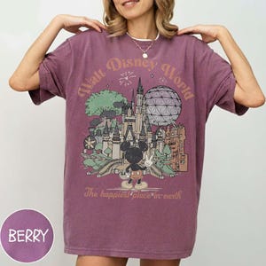 Puede incluir: Camiseta de color bayas con una ilustraci&oacute;n de estilo vintage de Walt Disney World. El dise&ntilde;o incluye un castillo, Spaceship Earth, Mickey Mouse y el texto "The happiest place on earth."