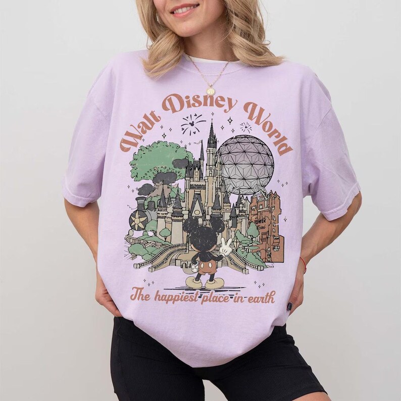 Puede incluir: Camiseta lila claro con un gr&aacute;fico del castillo de Walt Disney World, Spaceship Earth y Mickey Mouse. El texto "Walt Disney World" y "The happiest place in earth" est&aacute; impreso en la camiseta.