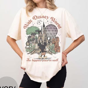 Puede incluir: Camiseta color marfil con un gr&aacute;fico vintage de Walt Disney World. El dise&ntilde;o incluye un castillo, Mickey Mouse y el texto "The happiest place on earth."