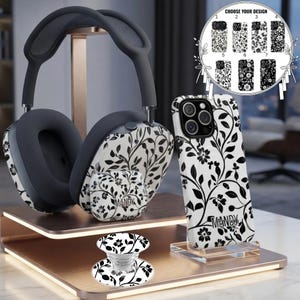 May include: A set of tech accessories featuring a black and white floral pattern, including over-ear headphones, a wireless earbud case, a phone case, and a circular phone grip. The phone case and earbud case are personalized with the name MANDY.