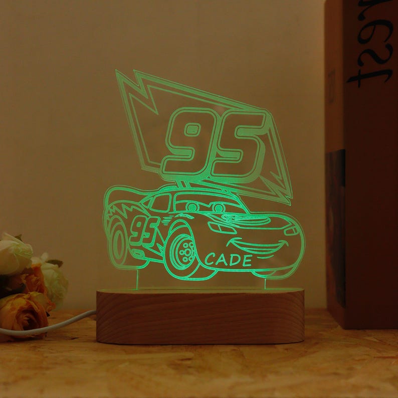 May include: A green neon light shaped like a race car with the number 95 and the name CADE. The light sits on a wooden base. The car is in a cartoon style.