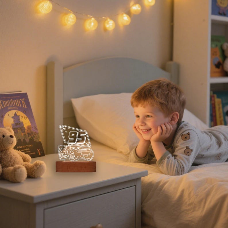 May include: A lit-up night light with a car design and the number "95" on a wooden base. The light is on a bedside table, with a child looking at the light.