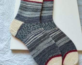 May include: A pair of gray and white striped socks with a red and white cuff. The socks have a subtle green pattern.