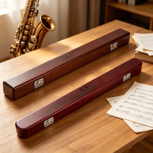 May include: Two long, rectangular, dark brown wooden cases with silver metal latches. The top case is engraved with the name Debi Pellhofer, and the bottom case is engraved with the initials AY and the name Alexandra Young in a dark font.