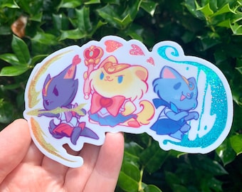 Puede incluir: Una pegatina con tres personajes de dibujos animados vestidos como exploradoras. Los personajes son un gato negro, un perro amarillo y un gato azul. La pegatina tiene un acabado brillante e iridiscente.