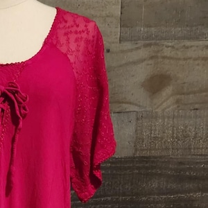 May include: A pink and white tie-dye maxi dress with a lace overlay on the sleeves. The dress has a round neckline and a drawstring at the waist.