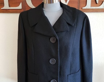May include: A black blazer with a classic design, featuring a notched collar, three buttons, and two front pockets. The jacket is displayed on a mannequin, showcasing its tailored fit and structured silhouette. The blazer is made of a textured fabric.