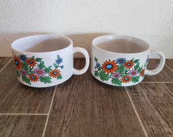 May include: Two white ceramic soup bowls with a floral design. The design features orange, pink, blue, and green flowers on a white background.