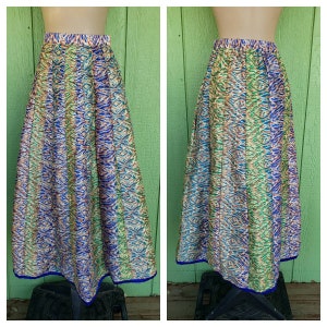 May include: A long, flowing skirt with a colorful, abstract print. The skirt has a blue waistband and a blue trim around the bottom.