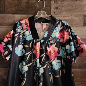 May include: A black short-sleeved nightgown with a floral print featuring pink, blue, and yellow flowers. The nightgown has a V-neck and a black trim around the neckline.