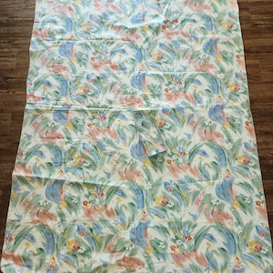 May include: A white tablecloth with a floral pattern in shades of blue, green, pink, and yellow. The pattern features abstract swirls and flowers.