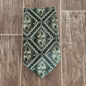 May include: A green necktie with a repeating pattern of stylized horses and riders in diamond shapes. The tie has a detailed design with various shades of green and white, creating a textured appearance.