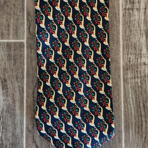 May include: A dark blue silk tie with a repeating pattern of gold trumpets and red and green bows.