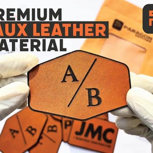 Puede incluir: Primer plano de material de cuero sintético con el texto "PREMIUM FAUX LEATHER MATERIAL". El material es de color naranja cálido, con las letras "A" y "B" impresas en negro. El material es sostenido por manos enguantadas.