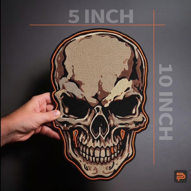 May include: A large skull patch, measuring approximately 25 cm tall and 13 cm wide, with a detailed design. The skull has a beige background with brown and black shading, and an orange border. The patch is held by a hand.