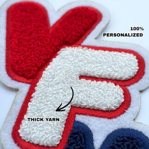 Può includere: Primo piano di una toppa personalizzata con la lettera "F" in bianco, rosso e blu. La "F" è realizzata con filato spesso e ha un bordo bianco. Il testo sulla toppa recita "100% PERSONALIZZATO" e "THICK YARN".