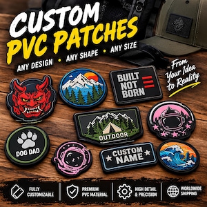 May include: A collection of custom PVC patches in various shapes and designs, including a red demon mask, a mountain landscape, a tent, an astronaut helmet, a dog paw print with the text DOG DAD, and a wave graphic, displayed on a wooden surface.