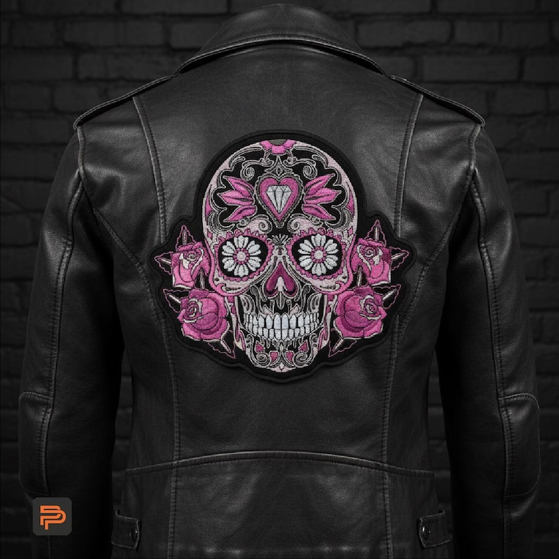 May include: Black leather jacket with a large embroidered patch featuring a sugar skull design. The skull is pink and white with floral and heart accents. Pink roses are on either side of the skull.