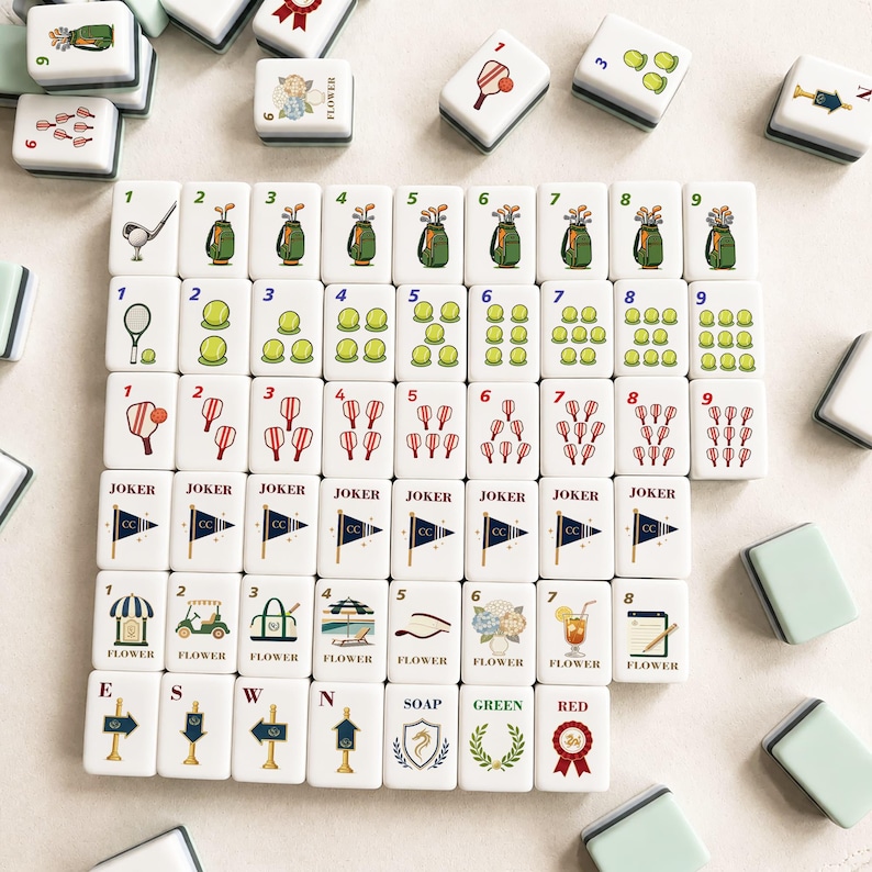 May include: A set of white Mahjong tiles with various illustrations, including golf clubs, tennis rackets, and floral designs. The tiles feature numbers, Jokers, and directional markers. Some tiles have the word "FLOWER".