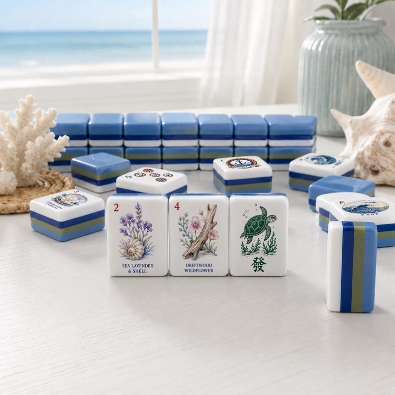 May include: A set of rectangular mahjong tiles featuring coastal-themed illustrations, including sea lavender, shells, driftwood, wildflowers, and a sea turtle. The tiles have white faces with colorful graphics and blue, green, and white striped sides.
