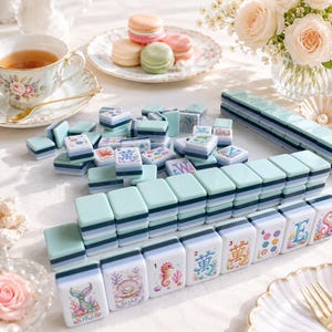 Op de afbeelding: Een verzameling pastelkleurige Mahjong-tegels met verschillende symbolen en illustraties, waaronder zeepaardjes, schelpen en Chinese karakters. De tegels zijn gerangschikt op een wit oppervlak, samen met een kopje thee, macarons en bloemen.