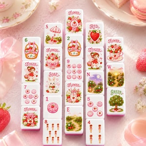 May include: A set of white mahjong tiles arranged in a grid, each featuring colourful illustrations of strawberries, flowers, cakes, and whimsical characters. The tiles include text labels such as Flower, Red, Green, Joker, Soap, and various numbers and letters.