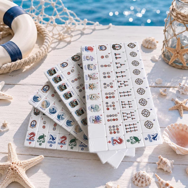 May include: A set of white Mahjong tiles featuring nautical illustrations including anchors, lighthouses, ship wheels, waves, sea creatures, and shells. The tiles are arranged in overlapping stacks on a white wooden surface with starfish.