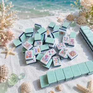 Op de afbeelding: Een verzameling turquoise en witte Mahjong-tegels met illustraties met een zeethema, waaronder zeesterren, schelpen en zeedieren. De tegels zijn gerangschikt op een wit oppervlak, met sommige tegels gestapeld en andere verspreid.