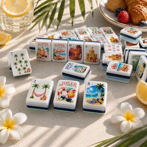 K&ouml;nnte beinhalten: Ein Satz dekorativer Mahjong-Steine mit Strandmotiven. Die Steine zeigen Bilder von Palmen, Strandszenen und tropischen Elementen. Die Steine sind wei&szlig; mit blauen und hellblauen Akzenten.