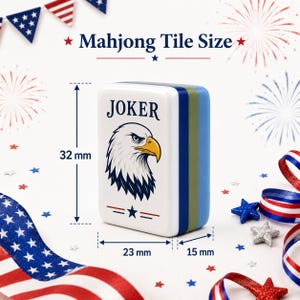 May include: A white Mahjong tile with a Joker design featuring an eagle illustration. The tile measures 32 mm high, 23 mm wide, and 15 mm thick. The tile has blue and green stripes on the side. The image includes patriotic decorations.