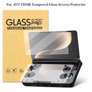 May include: A screen protector kit for the AYN THOR handheld gaming device. The kit includes a tempered glass screen protector and a cardboard box with the text "GLASS SCREEN PRO+ PREMIUM TEMPERED". The device is black with blue accents.