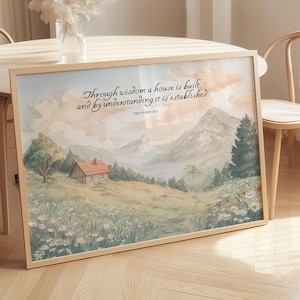 Pode incluir: Uma impressão em aquarela emoldurada com uma paisagem com uma casa, montanhas e flores silvestres. A impressão tem o texto "Through wisdom a house is built, and by understanding it is established. Provérbios 24:3."