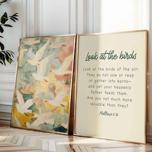 Puede incluir: Dos impresiones artísticas enmarcadas. Una presenta una pintura de pájaros blancos en vuelo sobre un fondo abstracto y colorido. La otra impresión tiene el texto "Look at the birds" y una cita de Mateo 6:26.