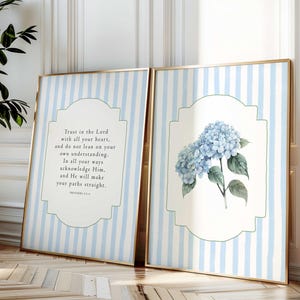 Könnte beinhalten: Zwei gerahmte Kunstdrucke. Einer zeigt Text aus Sprüche 3:5-6, der andere ein Aquarell von blauen Hortensien. Beide haben goldene Rahmen und einen hellblau-weiß gestreiften Hintergrund.