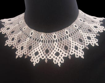 May include: A wide, collar-style necklace crafted from intricate white and translucent clear beads. The design features a repeating geometric lattice pattern with pointed, scalloped edges that drape around the neck, creating a lace-like effect.