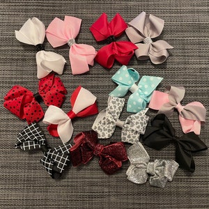 Könnte beinhalten: Eine Sammlung von 15 bunten Haarbändern mit verschiedenen Mustern und Designs. Die Schleifen sind aus verschiedenen Stoffen gefertigt und in einer Vielzahl von Farben erhältlich, darunter Rot, Pink, Blau, Weiß und Schwarz.
