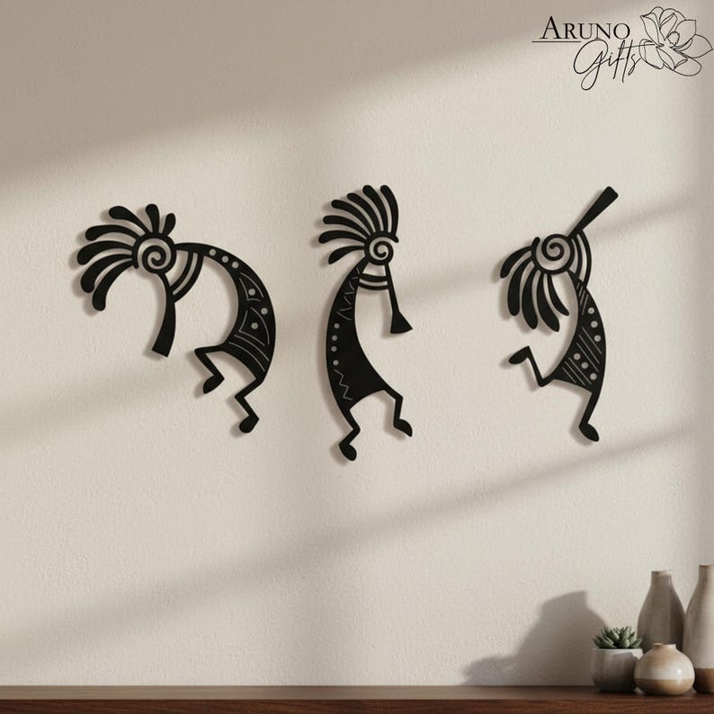 May include: Three black metal wall art pieces depicting stylized figures with headdresses and musical instruments. The figures are in various poses, with intricate patterns and details. The art is mounted on a light-coloured wall.