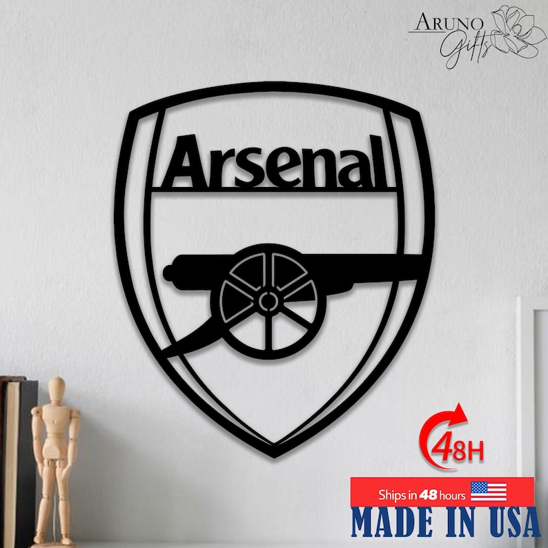 May include: Black metal wall art featuring the Arsenal logo, a shield with the word "Arsenal" and a cannon. The art piece is made in the USA. The image also includes the text "Ships in 48 hours".