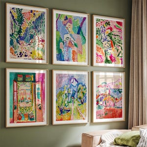 May include: Six framed art prints with colorful abstract paintings in a living room setting. The paintings feature vibrant hues of blue, green, pink, and yellow. The room has a modern aesthetic with a neutral-toned sofa and a round wooden coffee table.