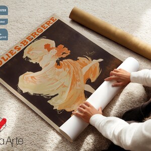 May include: An unframed poster with a vintage Folies Bergere advertisement, showing a woman in an orange dress. The poster is on enhanced matte photo paper. A rolled poster and a white roll of paper are also in the image.