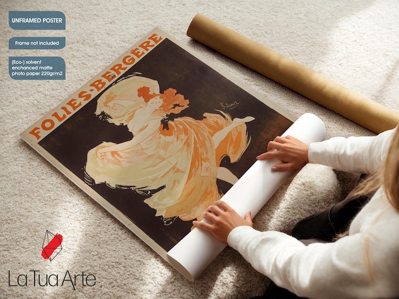 May include: An unframed poster with a vintage Folies Bergere advertisement, showing a woman in an orange dress. The poster is on enhanced matte photo paper. A rolled poster and a white roll of paper are also in the image.