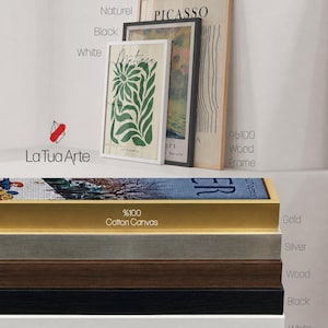 K&ouml;nnte beinhalten: Eine Sammlung gerahmter Kunstdrucke und Leinwandoptionen. Das Display umfasst drei vertikale Rahmen in Wei&szlig;, Schwarz und Naturholz sowie einen Stapel von f&uuml;nf horizontalen Leinwandrahmen in den Ausf&uuml;hrungen Gold, Silber, Holz, Schwarz und Wei&szlig;.
