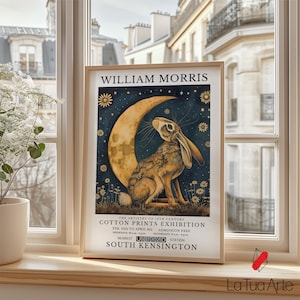 May include: A vintage poster advertising an exhibition of William Morris cotton prints. The poster features a stylized illustration of a hare sitting on a crescent moon with a starry night sky background. The text reads "The artistry of 19th century Cotton Prints Exhibition, Feb 10th to April 8th, Admission Free, Weekdays 10am to 6pm, Saturdays 11am to 4pm, Nearest Underground Station South Kensington."