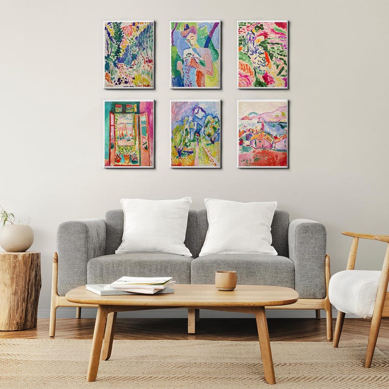 May include: Six framed art prints with colorful abstract landscape and figure paintings hang above a gray sofa. The paintings feature vibrant hues of green, blue, red, and yellow, creating a lively and artistic display in a living room setting.
