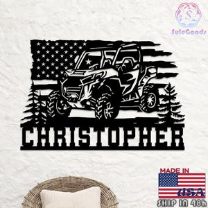 May include: Black metal wall art featuring a side-profile of an off-road vehicle, an American flag, and the name "CHRISTOPHER". The design includes pine trees and stars. The words "MADE IN USA" and a flag are also visible.